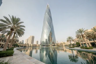 Vue en contre-plongée de l'Almas Tower dans le quartier JLT de Dubaï, reflet du gratte-ciel dans le lac artificiel au premier plan