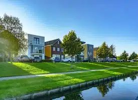white and brown house near green grass field and body of water during daytime